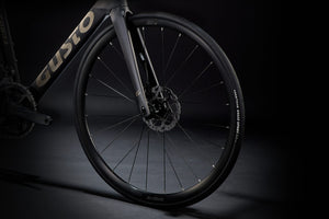 Close-up of a bicycle wheel with 'Custo' branding on a dark background